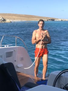 Cyclist takes a shower on a catamaran sailing boat while singing out loud