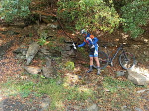 Mountain biker is filling his bottle from a water spring