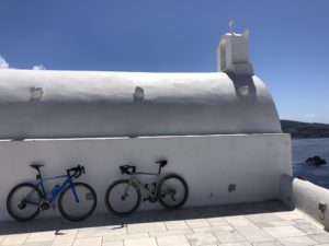 An iconic photo wth two road bikes in front of a white chapel and sea view in Santorini