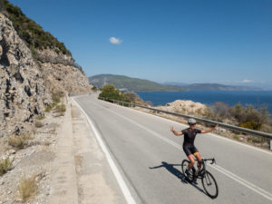 Road cyclist is cheering while cycling on the coastal road toward Porto Cheli and Epidaurus